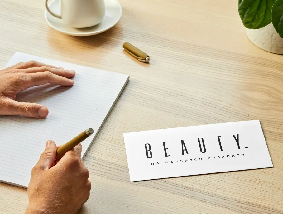 Wizytówka BEAUTY leżąca na biurku obok notatnika i długopisu